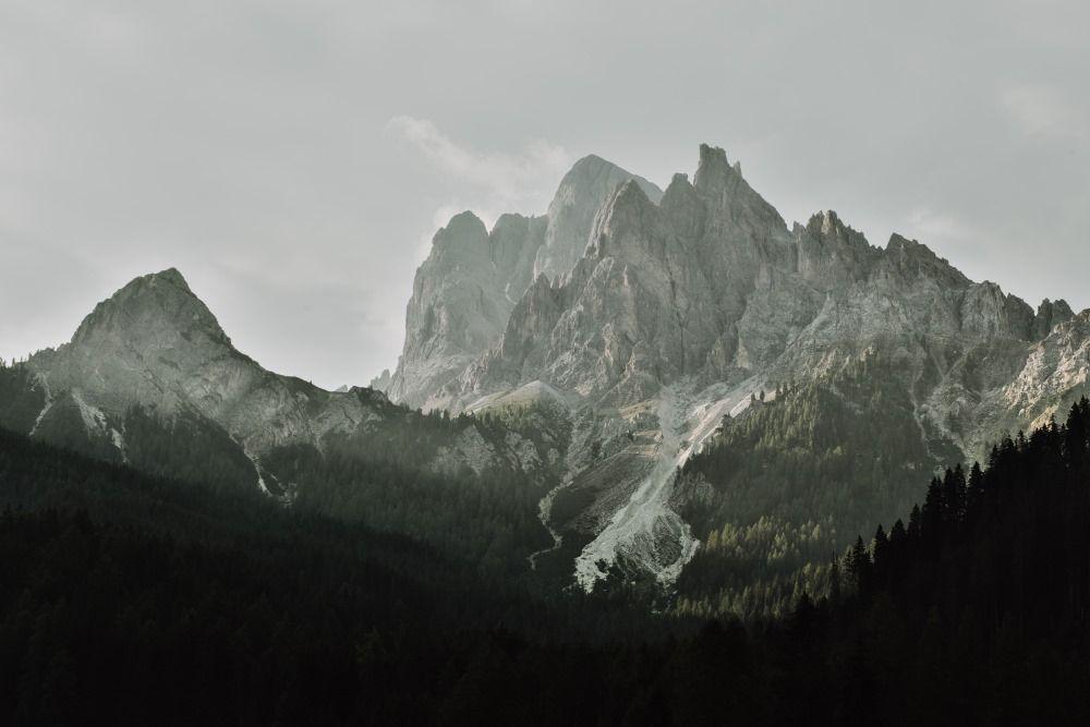 A mountain range with pine forests at the base.